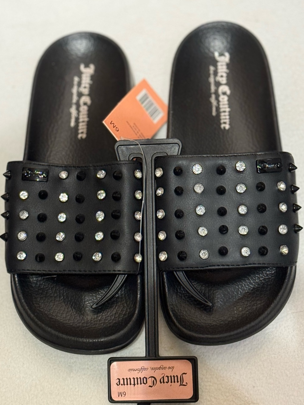 Juicy Couture black Slone slide sandals featuring pyramid studs and rhinestones.
